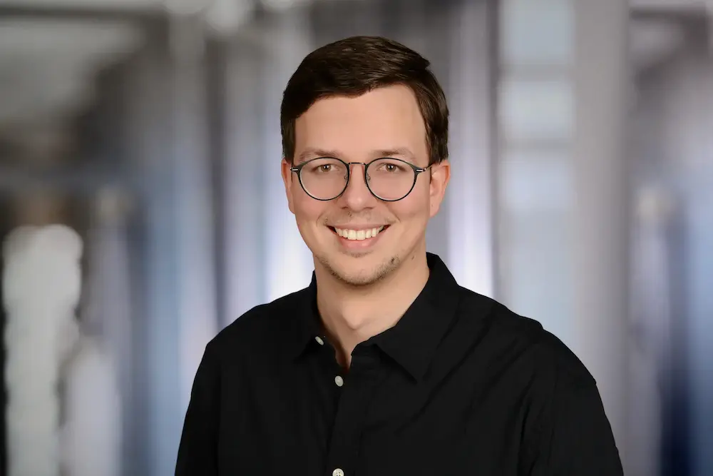 Porträt von Dmitry Dugarev mit Brille in einem schwarzen Hemd und mit einem Lächeln